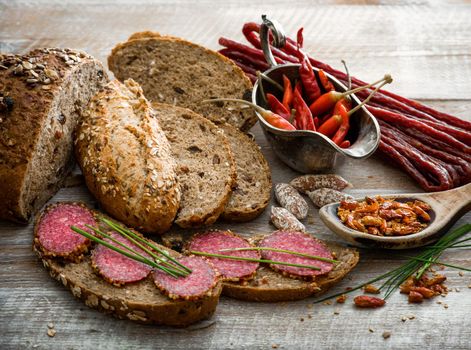 Wholemeal bread with sausages and other products on a rustic wooden table