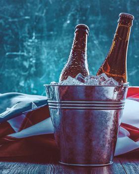 two bottles of beer in an ice bucket with the American flag lying nearby. Independence Day celebration concept