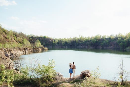 a young couple a guy and a girl are walking near a mountain lake surrounded by granite rocks