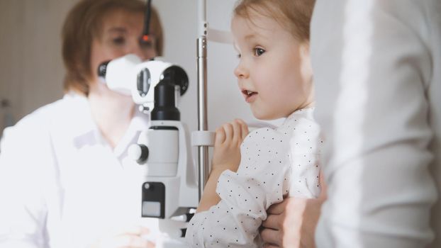 Little adorable girl in child's ophthalmology - optometrist checking eyesight, close up