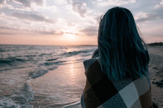 Unrecognizable woman enjoying view of sunset on sea coast.