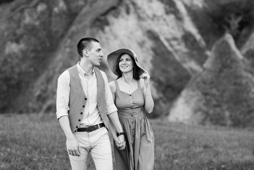 young couple a guy and a girl are walking in the green mountain hills