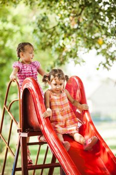 Two preschool girls on the slide at the playground