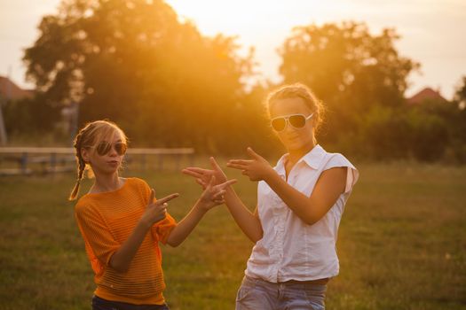 Two teenage girls have fun in the park. Two friends outdoor. Summer people in glasses