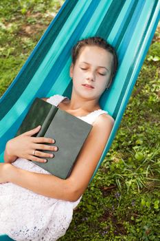 Romantic teenage girl lays on hammock with book of memories