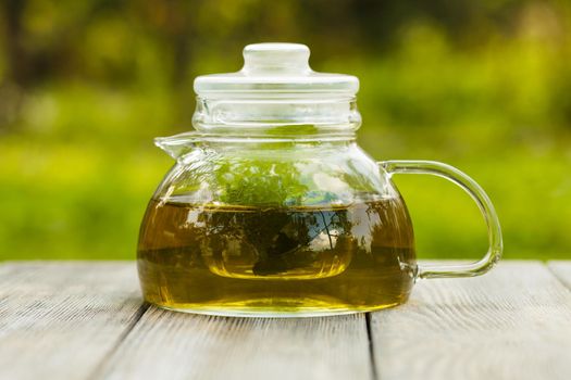 Herbal tea in a glass teapot on the table outdoor