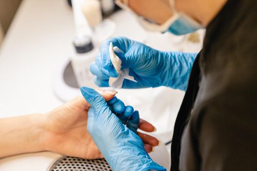 Aesthetician doing the manicure, filing the nails with a file to his client in a beauty center. Business and beauty concepts