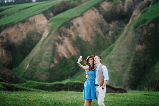 young couple a guy and a girl are walking in the green mountain hills