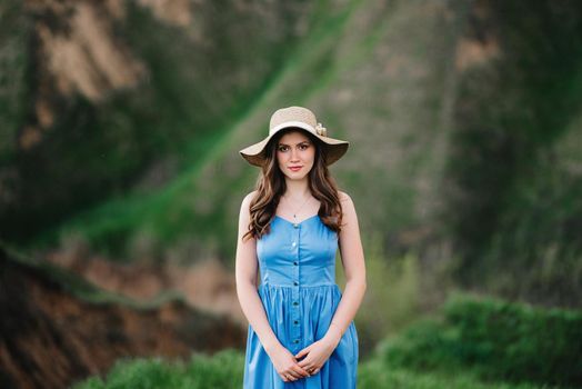 young girl in a straw hat with large brim on mountain green slopes