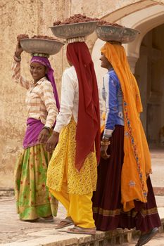 JAIPUR, RAJASTHAN, INDIA - JULY 30, 2008: Female laborers transporting water and plaster in bowls carried on the head during the restoration of a palace inside Amber Fort in Jaipur, Rajasthan, India.