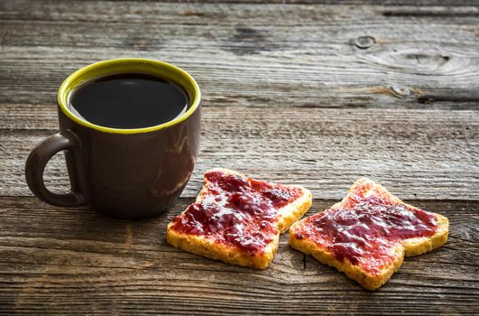 bread with jam and a cup of tea for breakfast on wooden background