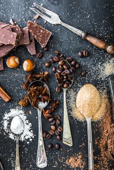 Sweet powdered ingredients in a spoon and chocolate on a table black