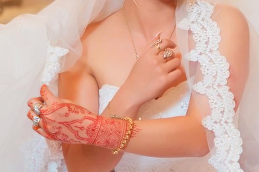 The bride holds the fat. The bride has handset, rings and bracelets. Elegant Wedding Ring with Beautiful Henna of Bride Hand