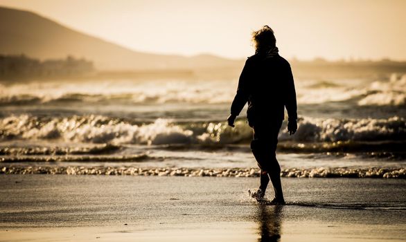 Silhouette of the man, walking on the ocean beach