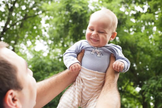 Father plays with son in a park. Flying baby