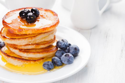 Pancakes with blueberry and honey on a white plate