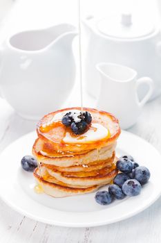 Pancakes with blueberry and honey on a white plate