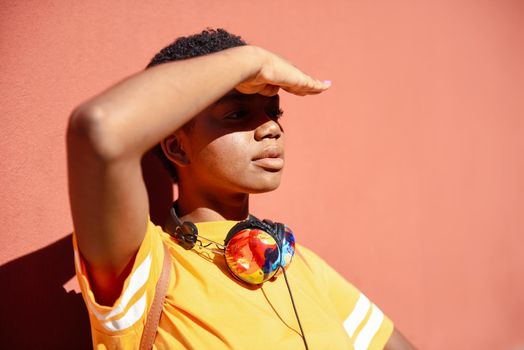 Young black woman covering with her hand the sun that falls on her eyes. Girl with very short hair.