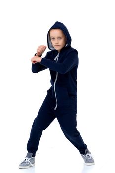 Preteen boy in blue warm overalls. Handsome stylish boy wearing hooded jumpsuit posing against white background in studio