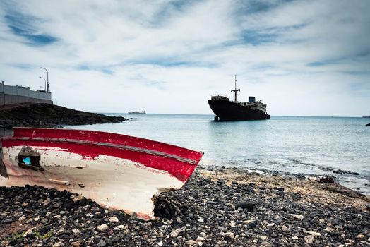 boat on the backgrond with old broken agrounded ship , Lanzarote, Canary Islands, Spain