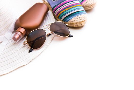 Beach accessories. Summer shoes and hat with sunglasses and suntan lotion on a white background