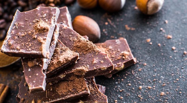 Chocolate and nuts on a black table with a worn surface