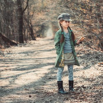 little girl playing with a slingshot in the woods, photo in vintage style