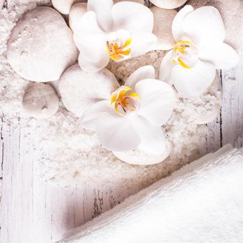 Sea salt, rebbles with orchids and white towels, spa concept