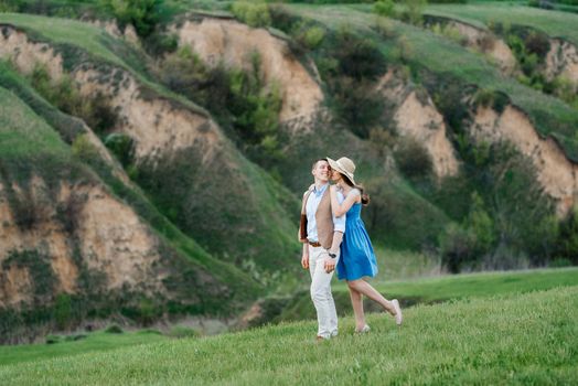 young couple a guy and a girl are walking in the green mountain hills