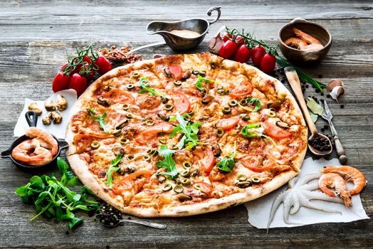 Big tasty pizza with seafood, tomatoes on a wooden table