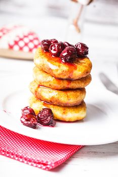 cheese pancakes with cherry jam on the plate