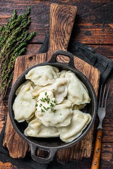 Homemade dumplings, vareniki, pierogi stuffed with potato in a pan. Dark wooden background. Top View.