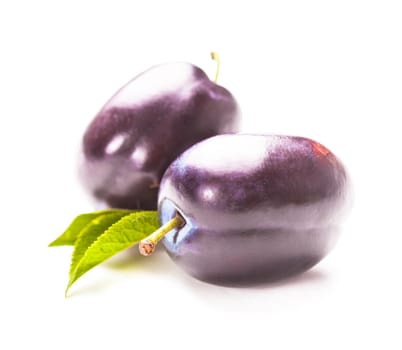 Plums with green leaf isolated on a white background