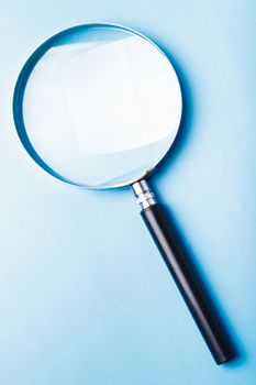 Glass magnifier closeup on a blue background