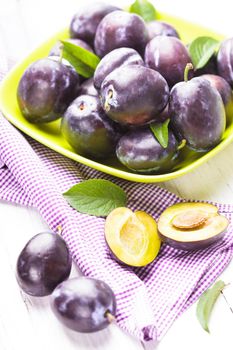 Fleshy plums in a bowl on the table