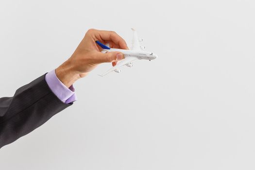 Adult businessman in suit holding a plane isolated on white