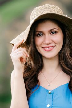 young girl in a straw hat with large brim on mountain green slopes