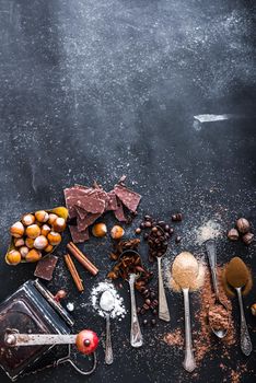 Sweet spices in the spoons and chocolate on a table black