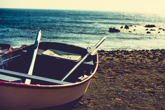 boat on a sandy shore on rocky coastline background