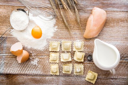 Tortellini on wooden board with chicken and other products