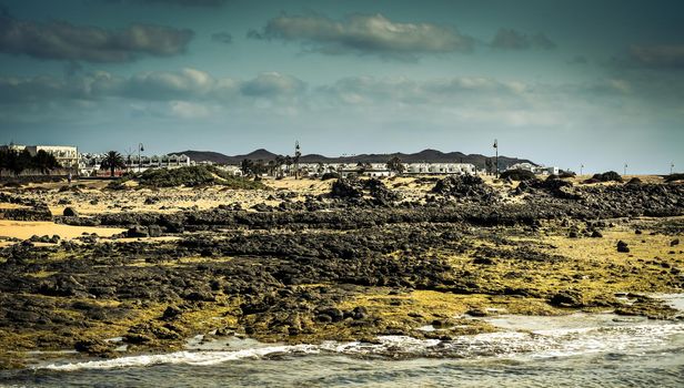 desert Lanzarote coast with a township on the background, Canary Islands, Spain