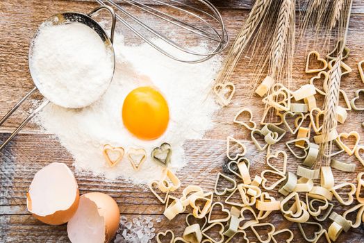 Heart shaped pasta and other products on a wooden textured table