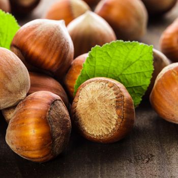 Hazelnuts with shell and green leaf on the wooden table