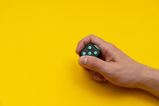 Antistress fidget in mans right hand on yellow background, close up, copy space