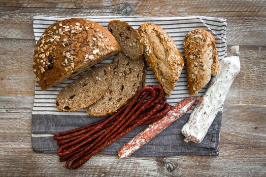 Wholemeal bread with dried sausages on a rustic wooden table
