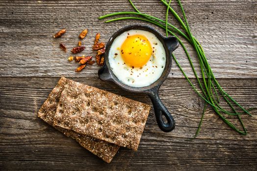 breakfast with fried egg, wheat bread and thyme on wooden background