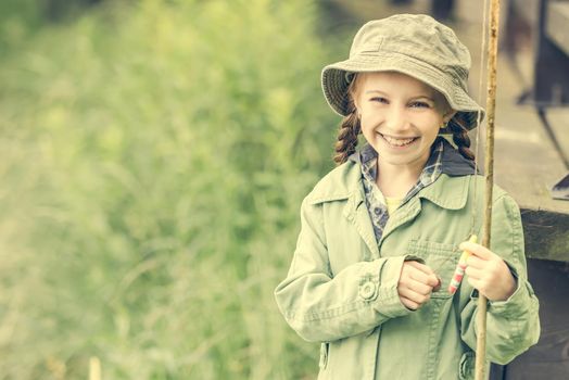 little fisher girl smiles holding a rod