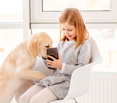 Cute little girl showing phone to curious dog