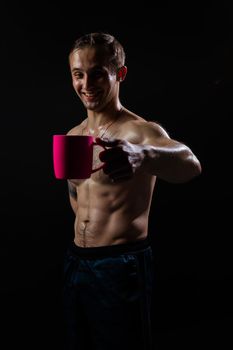 Man on black background keeps dumbbells pumped up in fitness torso, athlete weight man bodybuilder hand, shirtless lifestyle. Young handsome metal, human fit In the athlete's pink cup he smiles