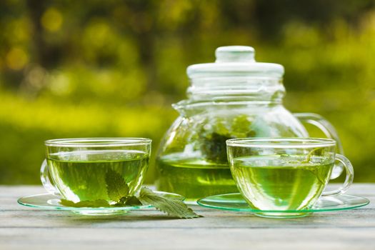 Herbal tea with melissa in a glass cup and teapot